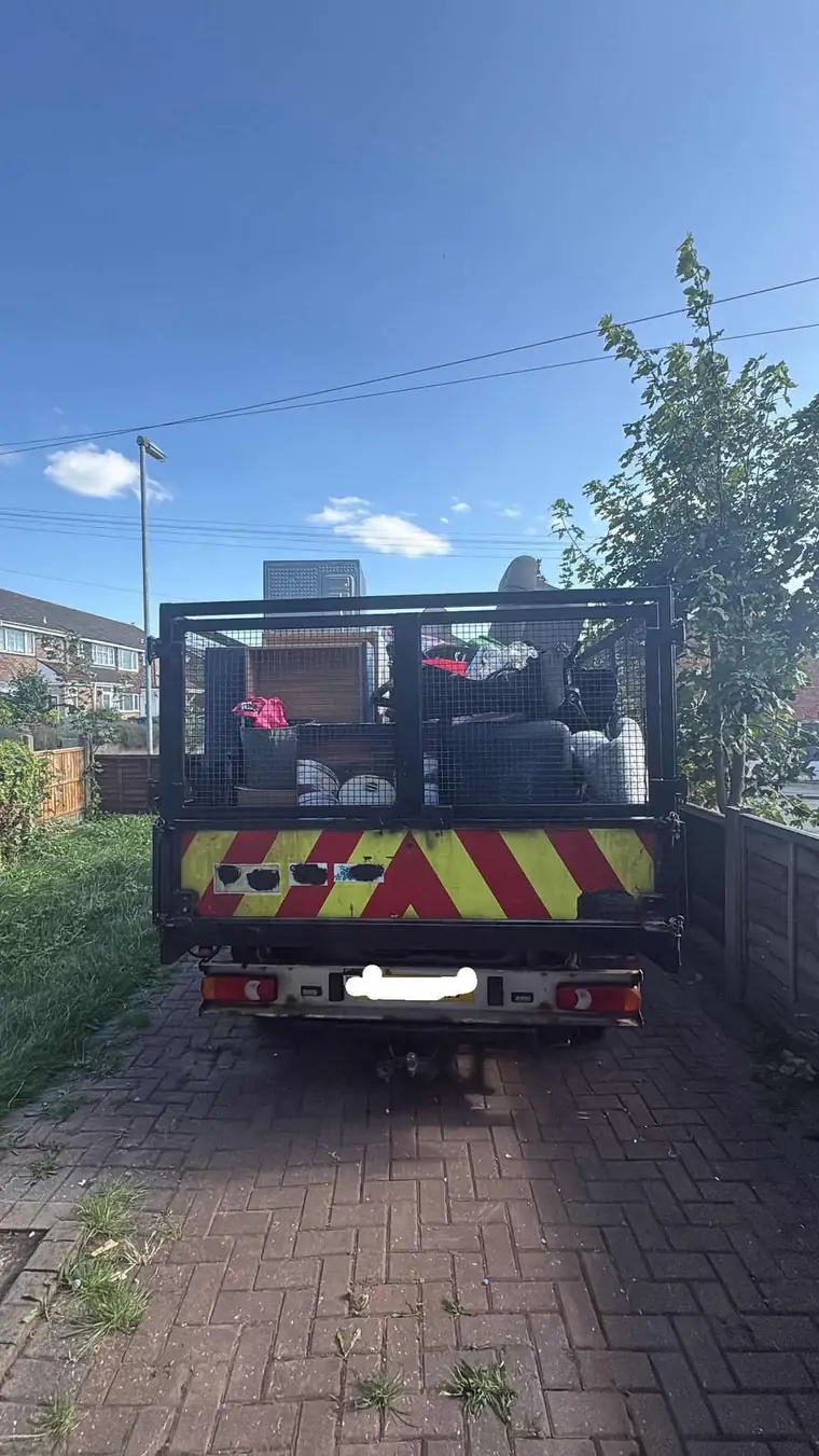 A caged tipper truck fully loaded with old furniture and appliances