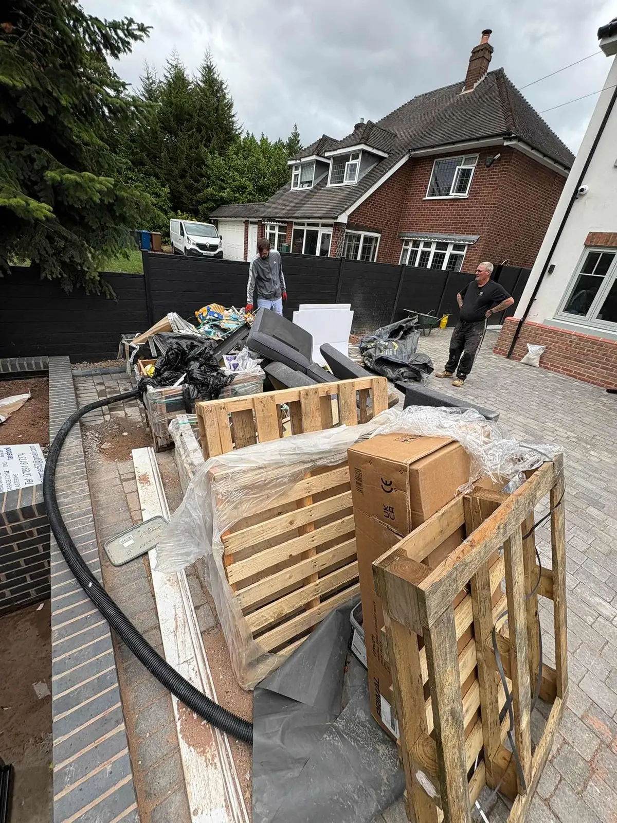 A driveway piled with renovation waste, pallets, old sofas and boxes before clearance