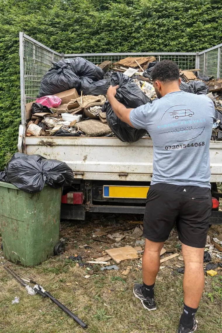 Team member loading rubbish into a caged tipper truck for responsible disposal